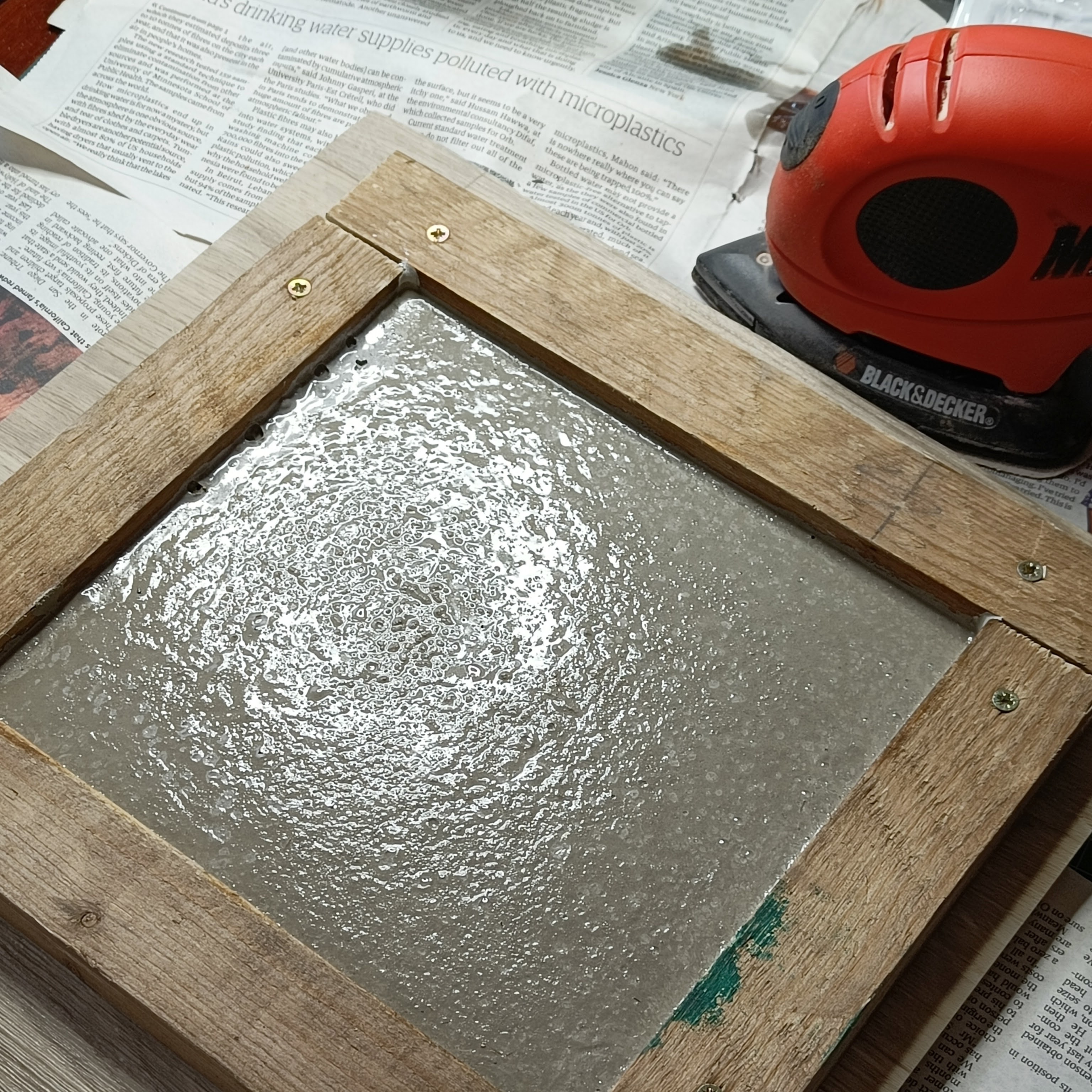 magically, the surface of the concrete in the frame has
  been made level and appears with that wet slightly bubbly
  texture that is familiar from movies scenes where someone is
  about to step into wet concrete. The mouse sander responsible
  for the vibrating that made this happen rests nearby.