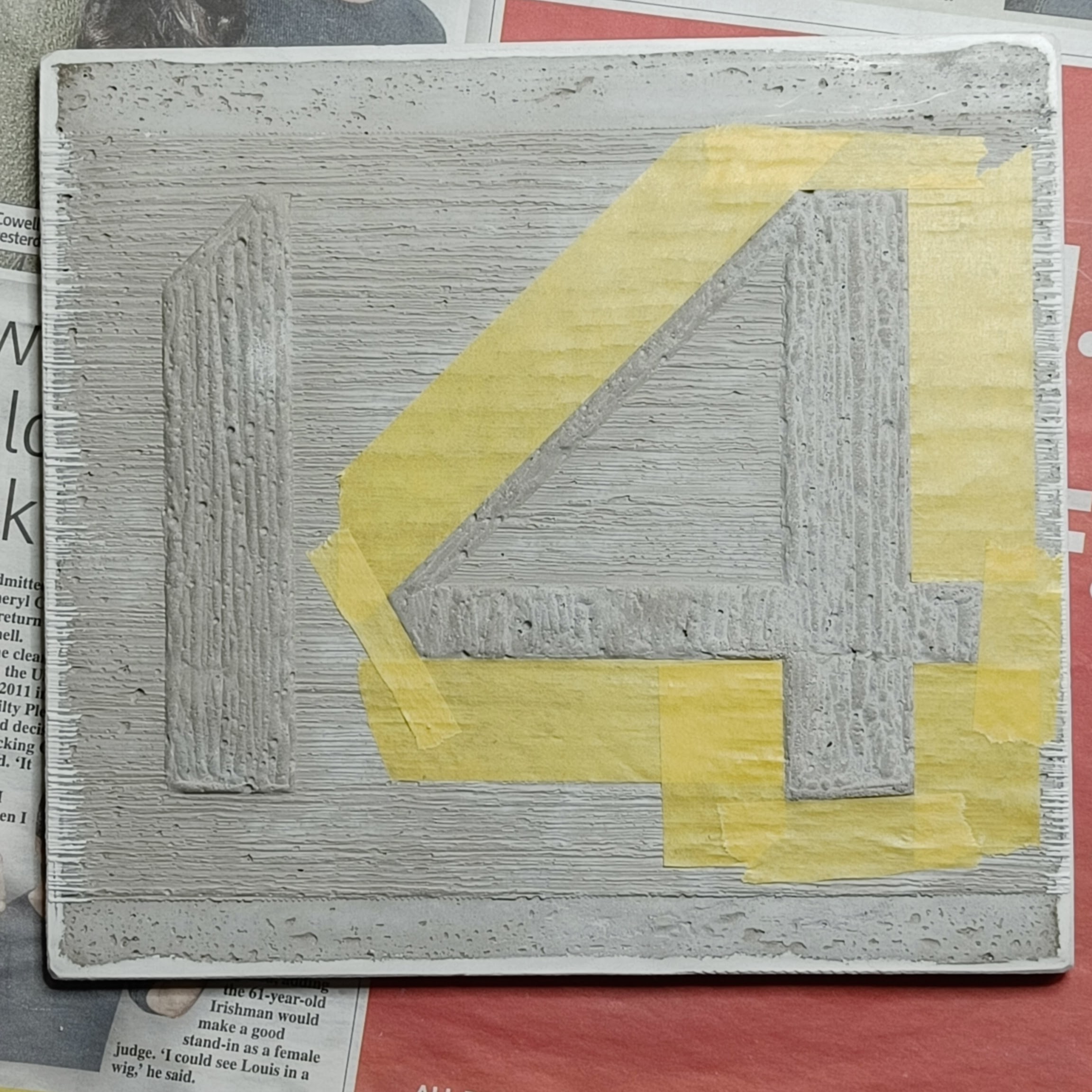a concrete plaque showing a number 14. The 4 has been
  carefully taped around its outside outline, using quite a
  large number of pieces of yellow tape.